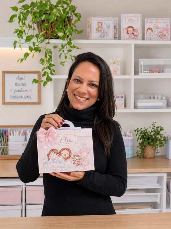 Naty Costa no ateliê, segurando uma caixinha personalizada
